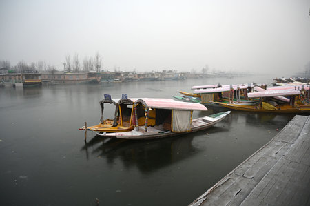 SRINAGAR, INDIA - DECEMBER 25: Boats docked on a frozen surface of Dal Lake on a cold morning, on December 25, 2024 in Srinagar, India. Kashmir is witnessing freezing night temperatures with Srinagar recorded minus 7.3 degrees Celsius. (Photo by Waseem Anのeditorial素材