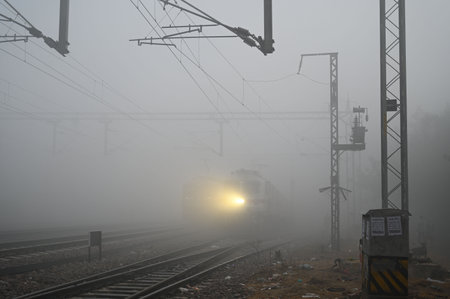 GURUGRAM, INDIA - DECEMBER 25: A passenger train moving from Gurugram to Rewari amid dense fog at Gurugram Railway Station near Rajendra Park, on December 25, 2024 in Gurugram, India. A cold wave has hit India, leaving several states grappling with extremのeditorial素材