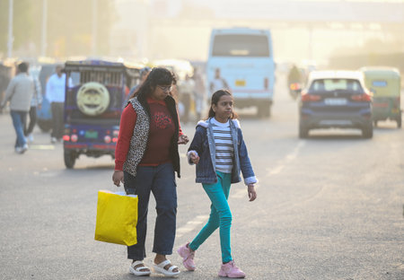 NOIDA, INDIA - JANUARY 5: Commuters step out on a cold evening amid rising air pollution on Sector 38 Road , on January 5, 2025 in Noida, India. A dense blanket of fog once again engulfed national capital Delhi on Saturday morning reducing the visibility のeditorial素材