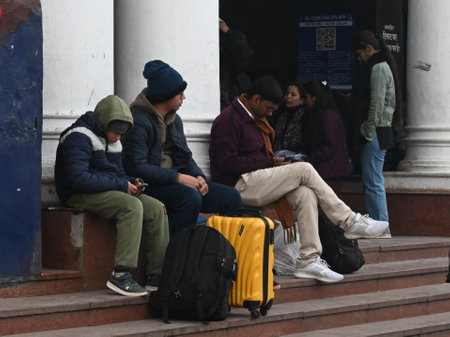 NEW DELHI, INDIA - JANUARY 4: Passengers sit on a platform covering themselves with woolen cloths at New Delhi Railway Station, several train services are impacted due to dense fog, on January 4, 2025 in New Delhi, India. A dense blanket of fog once againのeditorial素材
