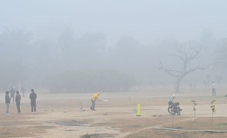 NEW DELHI, INDIA - JANUARY 5: people playing cricket amidst early morning winter chill and fog in Dwarka, on January 5, 2025 in New Delhi, India. A dense blanket of fog once again engulfed national capital Delhi on Saturday morning reducing the visibilityのeditorial素材