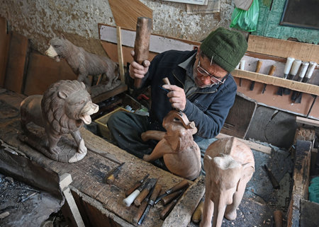 SRINAGAR INDIA FEBRUARY 24 2025 Walnut wood carving deaf mute artisan Mohammed Yousaf Muran works on a handcrafted walnut wood piece at his workshop in downtown area on February 24 2025 in Srinagar India Kashmir is home to the world s finest walnut wood aのeditorial素材