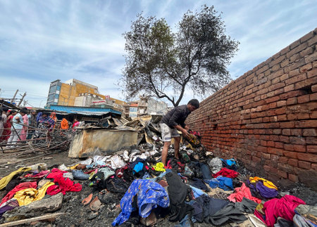 GURUGRAM, INDIA - MARCH 29: People salvage charred belongings from a site where a massive fire erupted at a slum area market in Basai Enclave sector-9B near Basai chowk, on March 29, 2025 in Gurugram, India. No one was injured in this incident. Six fire tのeditorial素材