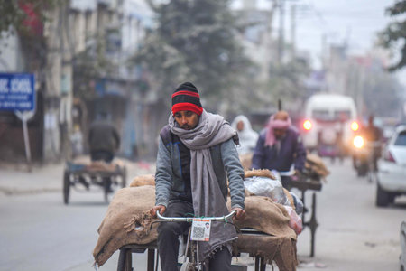 GURUGRAM, INDIA â€“ JANUARY 2: A man pulls a rickshaw cart wearing warm clothes on a cold...