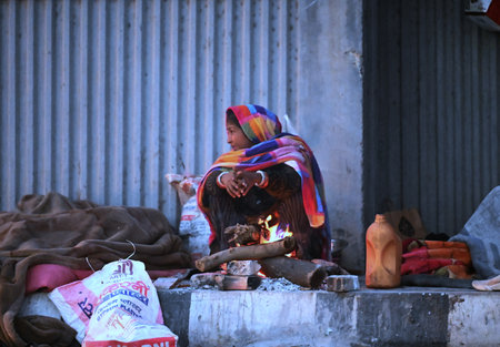 NEW DELHI, INDIA â€“ JANUARY 3: A woman sits near a bonfire on pavement as Delhiites brave the...