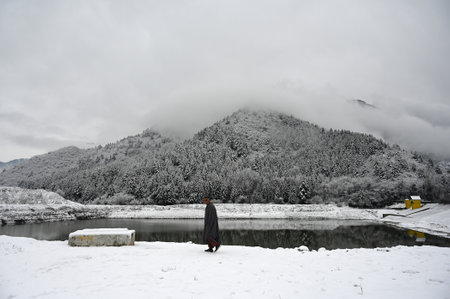 SRINAGAR, INDIA - FEBRUARY 1: A man walks after a seasons first snowfall on February 1, 2024 in the outskirts of Srinagar, India. It is the season---s first snowfall in the plains of the Kashmir valley, including in the summer capital Srinagar, which had のeditorial素材
