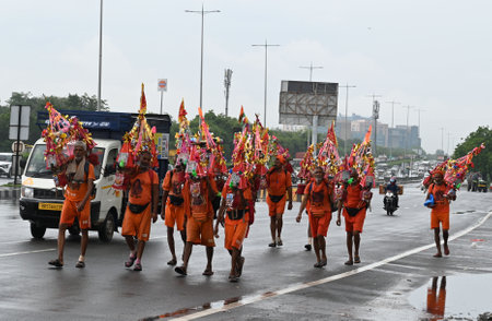 GURUGRAM, INDIA - JULY 8: Hindu devotees on 'Kanwar Yatra' walking during heavy rains carrying holy water from the Ganges River in the holy month of Shravan near Rajiv chowk, on July 8, 2023 in Gurugram, India. Delhi-NCR was drenched with heavy rain on thのeditorial素材