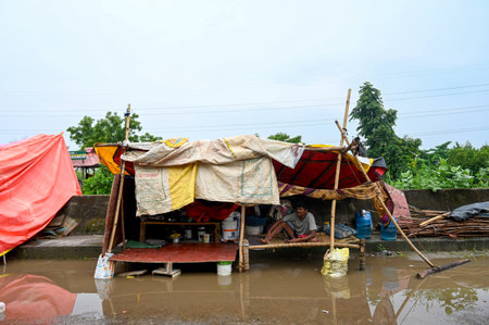 NOIDA, INDIA - JULY 18: People residing near low-lying areas around the Yamuna River in sector 128 relocate to makeshift tents after their houses were submerged as the Yamuna River swells up, on July 18, 2023 in Noida, India. (Photo by Sunil Ghosh/Hindustのeditorial素材