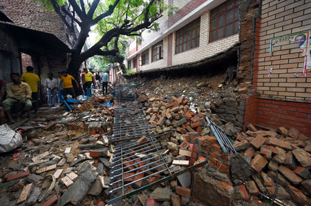 NEW DELHI, INDIA - JULY 9: Locals at the site after a wall of a government school in Garhi collapsed following monsoon rains,, on July 9, 2023 in New Delhi, India. Delhi-NCR was drenched with heavy rain on the intervening night of Friday, Saturday and Sunのeditorial素材