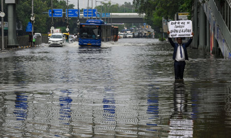NEW DELHI INDIA JULY 15 2023 A man hold Poster against Delhi CM Arvind Kejriwal through the waterlogged ITO Viaks Marg due to the rise in water levels of Yamuna river following heavy monsoon rains on July 15 2023 in New Delhi India The water level of the のeditorial素材