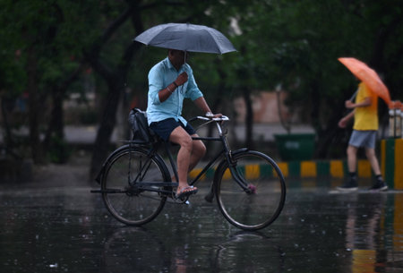 NOIDA INDIA JUNE 25 2023 Commuters out in the light rain on the Sector 21 road on June 25 2023 in Noida India Heavy rainfall accompanied by lightning lashed several parts of the national capital Delhi and its adjoining areas in the early hours of Sunday Tのeditorial素材