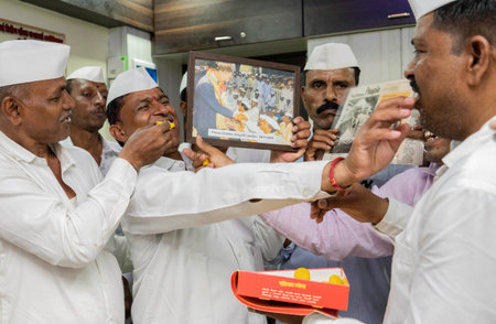 MUMBAI INDIA MAY 6 2023 Mumbai dabbawalas feed sweets to one another in celebration after Prince Charles was crowned as King Charles III as the 40th monarch of Britain during a coronation ceremony at Westminster Abbey in a central London church at their Dのeditorial素材