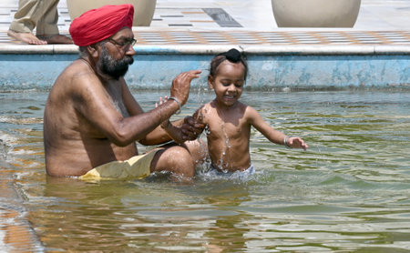NEW DELHI INDIA APRIL 14 2023 Devotees take a dip in the sacred pond of Gurudwara Bangla Sahib on the occasion of Vaisakhi festival on April 14 2023 in New Delhi India Baisakhi also known as Vaisakhi is an important and popular harvest festival celebratedのeditorial素材