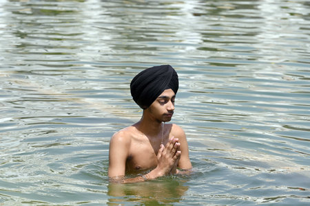NEW DELHI INDIA APRIL 14 2023 Devotees take a dip in the sacred pond of Gurudwara Bangla Sahib on the occasion of Vaisakhi festival on April 14 2023 in New Delhi India Baisakhi also known as Vaisakhi is an important and popular harvest festival celebratedのeditorial素材