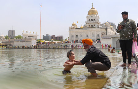 NEW DELHI INDIA APRIL 14 2023 Devotees take a dip in the sacred pond of Gurudwara Bangla Sahib on...