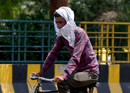 NOIDA INDIA APRIL 18 2023 Commuter seen with his head wrapped in towel to protect them from the severe heat wave at sector 38 on April 18 2023 in Noida India Delhi registered a maximum temperature of 40 4 degrees Celsius four notches higher than normal thのeditorial素材