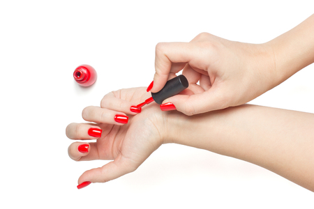 Woman applying red nail polish her nails manicure on white background isolatedの写真素材