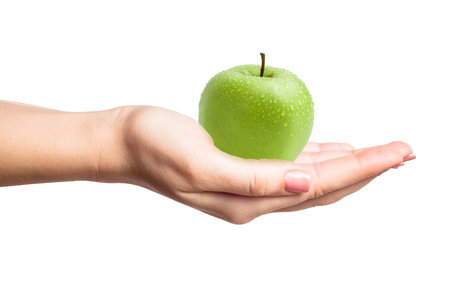 Beautiful female manicured hand holding a perfect green apple with water drops isolatedの写真素材