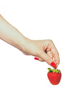 Woman manicured hands whith red nails polish holding fresh strawberries on white background.の写真素材