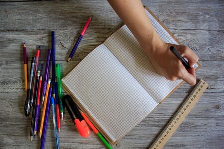 Right-handed woman holding pen while writing on small notebook on wooden rusty floorの写真素材