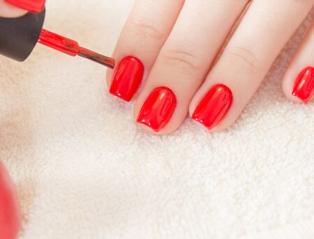 Manicure - Beautiful manicured womans nails with red nail polish on soft white towel.の写真素材
