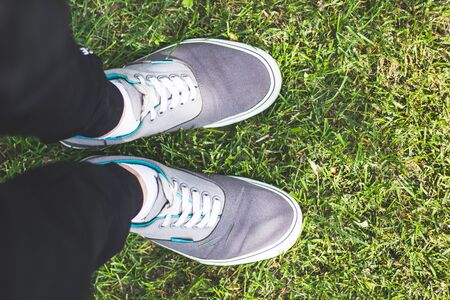 Feet selfie with fashion sneakers on grass background, top view with copy spaceの写真素材