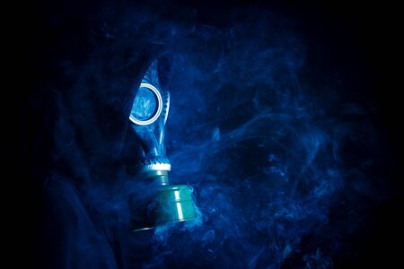 Dramatic portrait of man in gas mask and smoke on black backgroundの写真素材