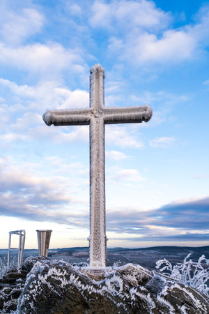 Summit Cross heavily freezed with snow and ice at cloudy blue skyの写真素材