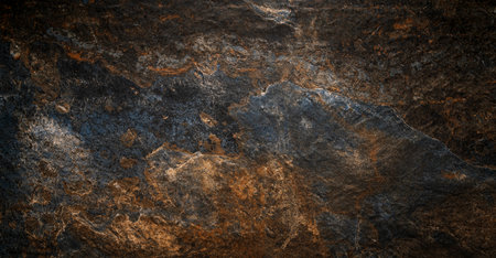 A close-up view of a dark textured stone surface showing intricate natural patterns and colors.の写真素材