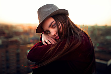Portrait of a girl in a hat on the background of the evening city
