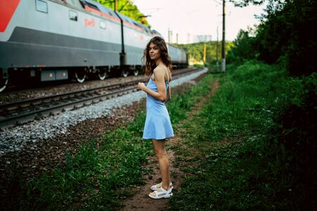 A girl in a delicate blue dress walks along a path on the top of a mountain near the riverの写真素材