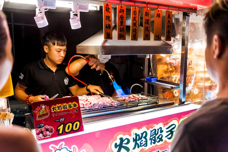 Kenting, Taiwan - JULY 15, 2015: Vendor prepares food at the Kenting main street night market located in Pingtung County.のeditorial素材