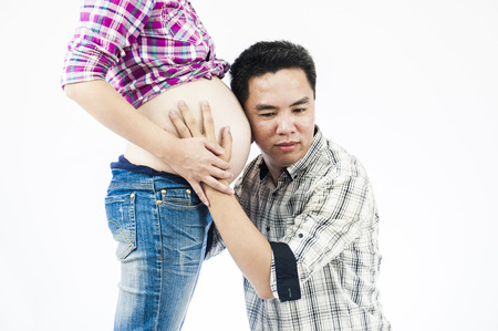 Image of pregnant couple. Husband touching his wife belly with handsの写真素材
