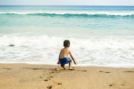 Little baby boy sitting on the sandの写真素材