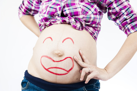 Pregnancy and skin care. belly of pregnant woman and smile from moisturizing cream for stretch marksの写真素材