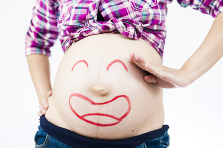 Pregnancy and skin care. belly of pregnant woman and smile from moisturizing cream for stretch marksの写真素材