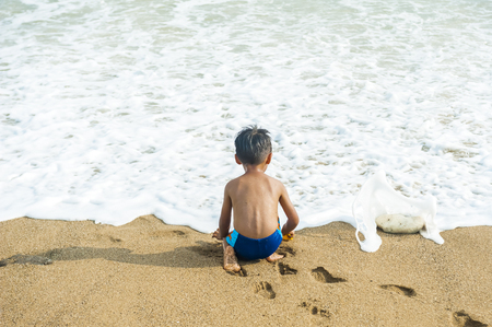 Little baby boy sitting on the sandの写真素材