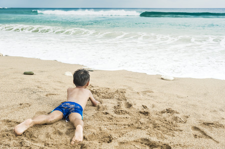 Little baby boy sitting on the sandの写真素材