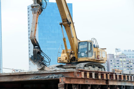 KAOHSIUNG, TAIWAN -- JUNE 14, 2016: An excavator drives a pile into the river bed as construction of...