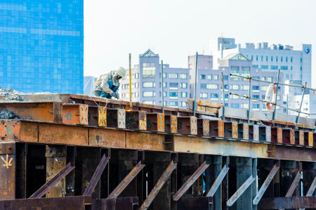 KAOHSIUNG, TAIWAN -- JUNE 14, 2016: An excavator drives a pile into the river bed as construction of...