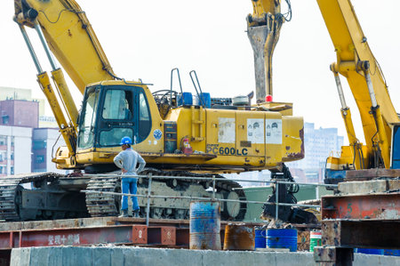 KAOHSIUNG, TAIWAN -- JUNE 14, 2016: An excavator drives a pile into the river bed as construction of...