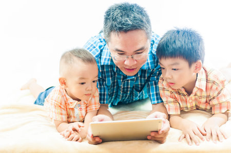 business father at home concept- father of two kids in business style with touch pad at homeの写真素材