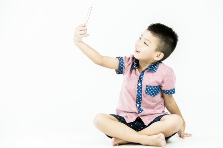 boy playing in a mobile phone on an isolated white backgroundの写真素材