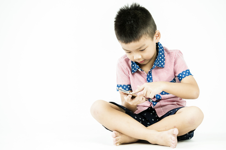 boy playing in a mobile phone on an isolated white backgroundの写真素材