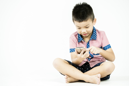 boy playing in a mobile phone on an isolated white backgroundの写真素材