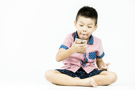 boy playing in a mobile phone on an isolated white backgroundの写真素材