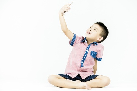boy playing in a mobile phone on an isolated white backgroundの写真素材