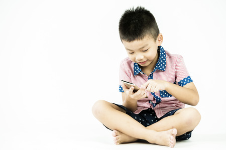 boy playing in a mobile phone on an isolated white backgroundの写真素材