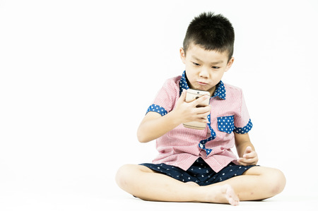 boy playing in a mobile phone on an isolated white backgroundの写真素材