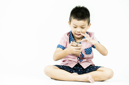 boy playing in a mobile phone on an isolated white backgroundの写真素材